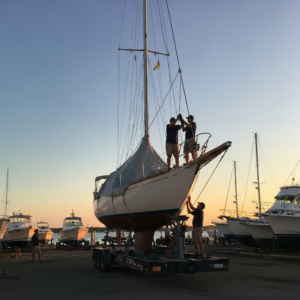 Classic Sailboats Boat Transport crew preparing a classic sloop for overland hauling with mast secured and cradle checked on the trailer